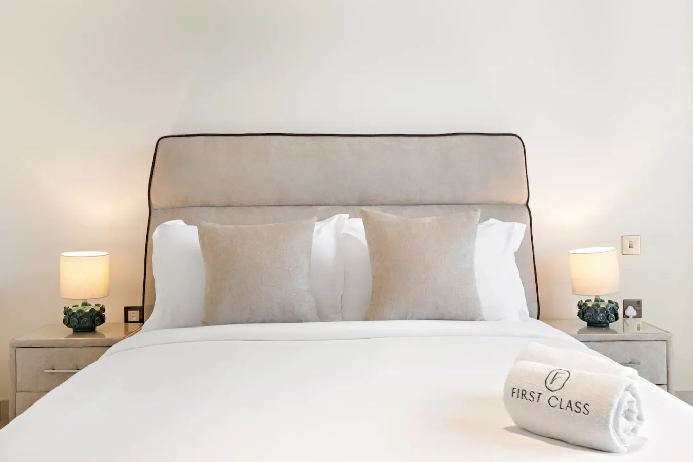 A neatly made bed with white bedding and bedside lamps.