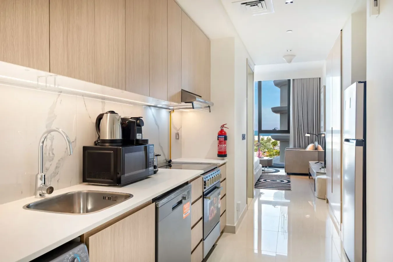 Una cocina compacta con fregadero y microondas da a una luminosa sala de estar.