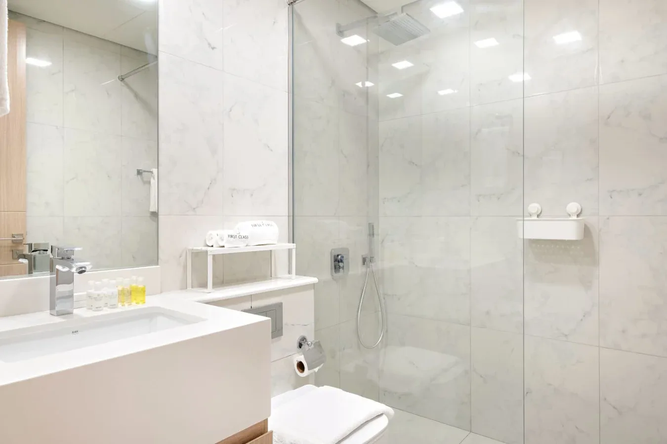 A bright bathroom with a sink, mirror, and shower.