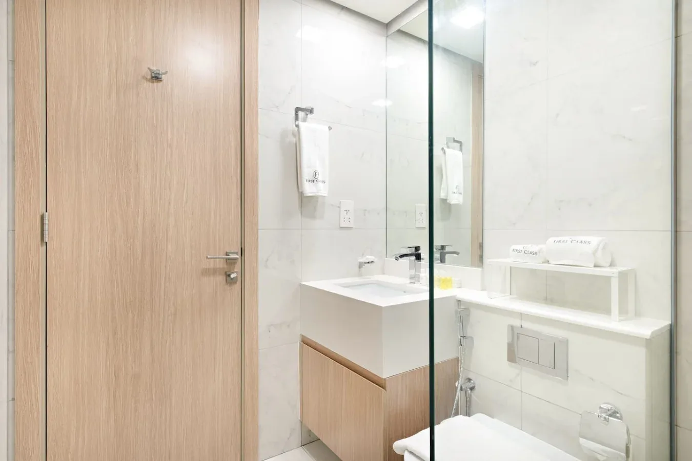 A modern bathroom with a vanity, mirror, and glass shower panel.