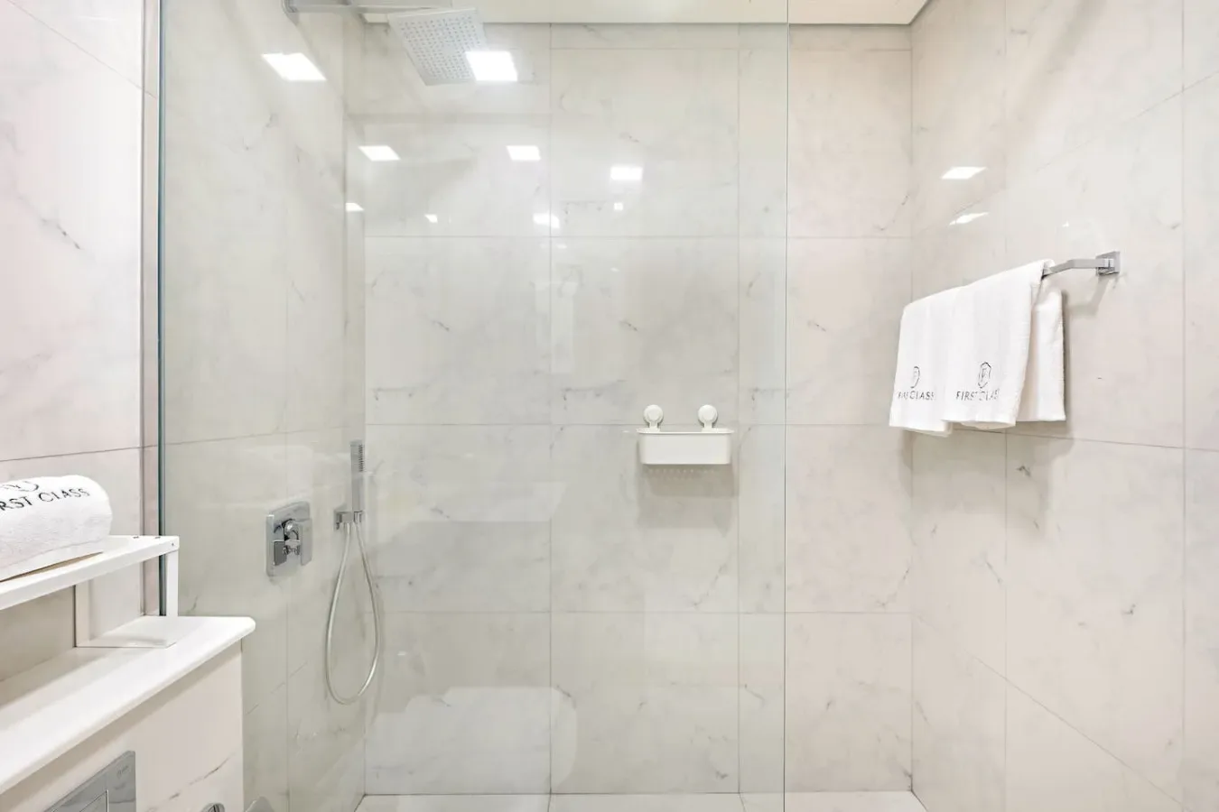 A bright bathroom with a glass shower and light-colored tiled walls.