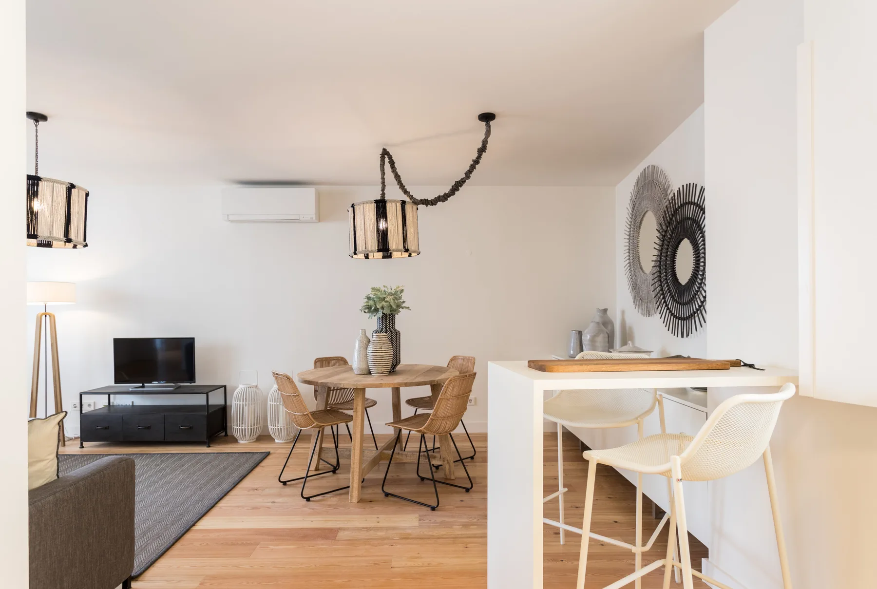A bright living and dining area with a table, seating, and a television.