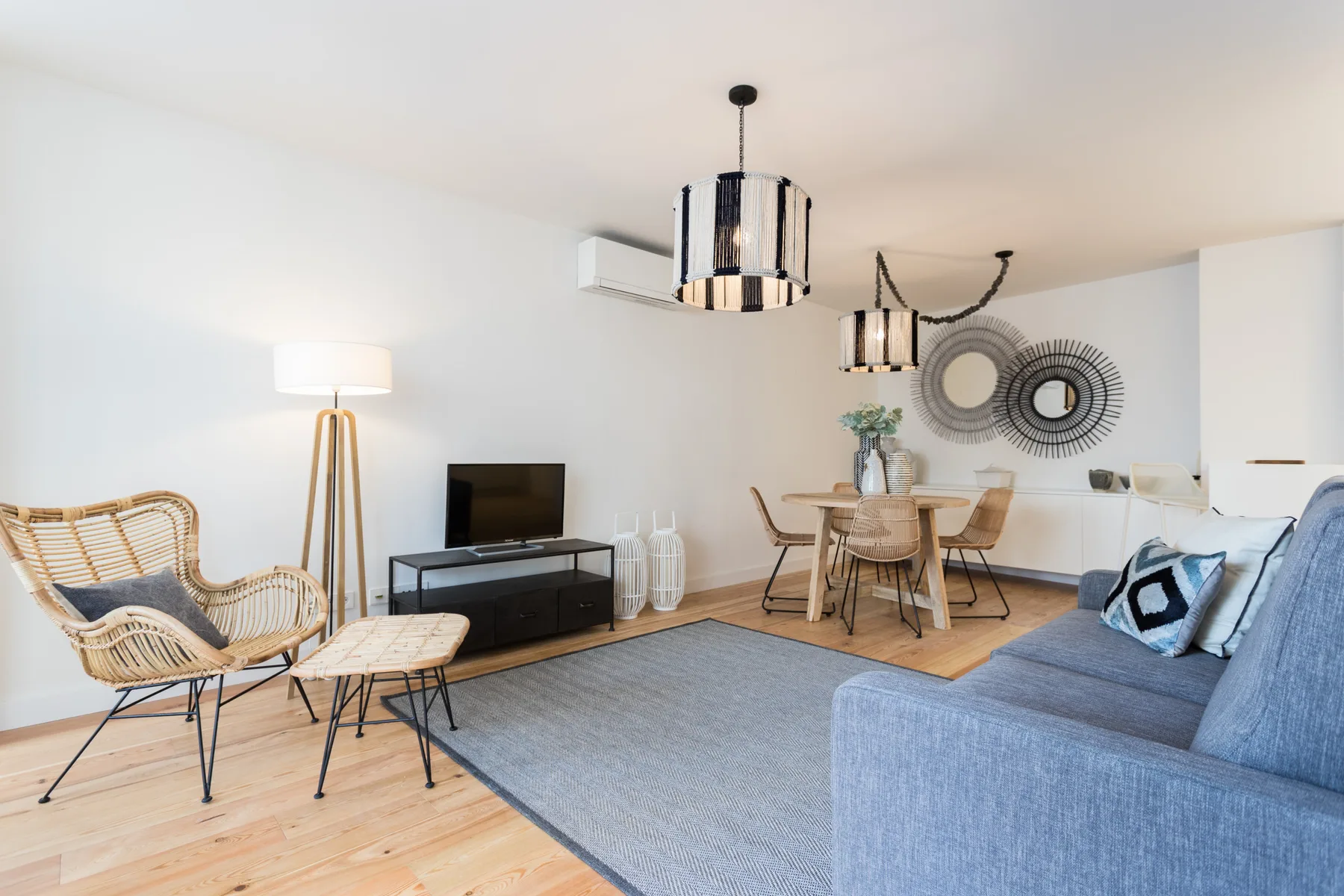 A bright living and dining area with a blue sofa and a round dining table.