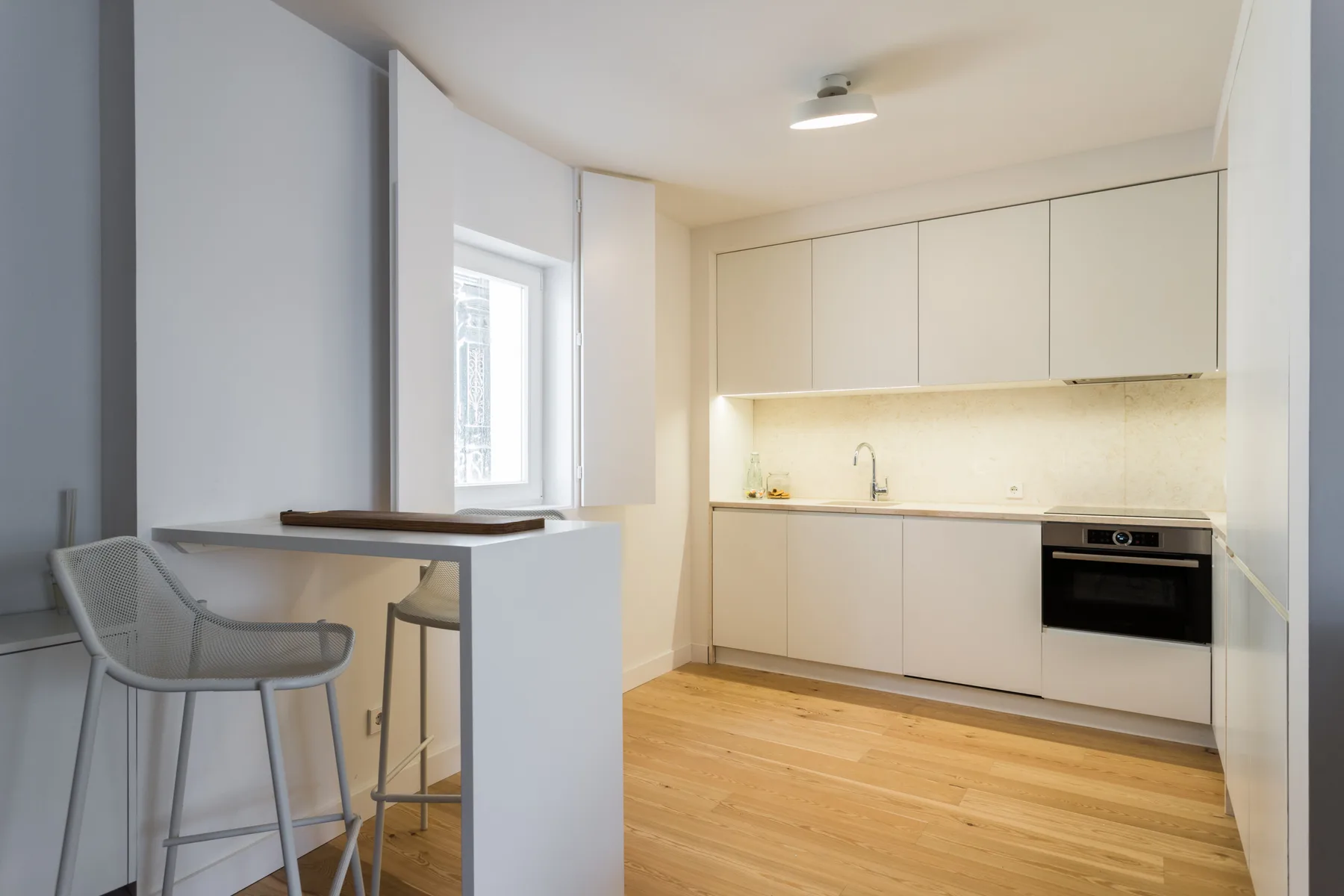 A bright kitchen with pale cabinets, a countertop, and light wood flooring.