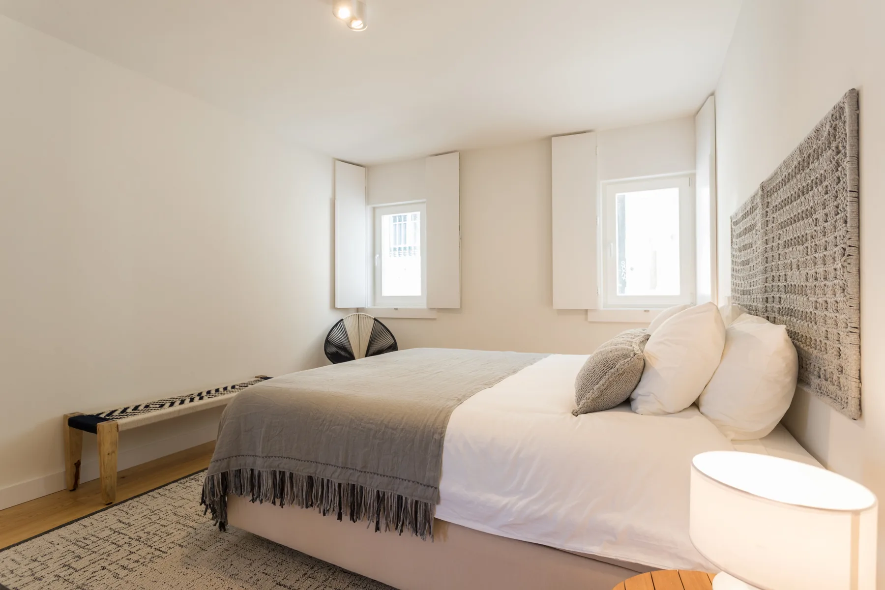 Un dormitorio luminoso con una cama grande y dos ventanas.