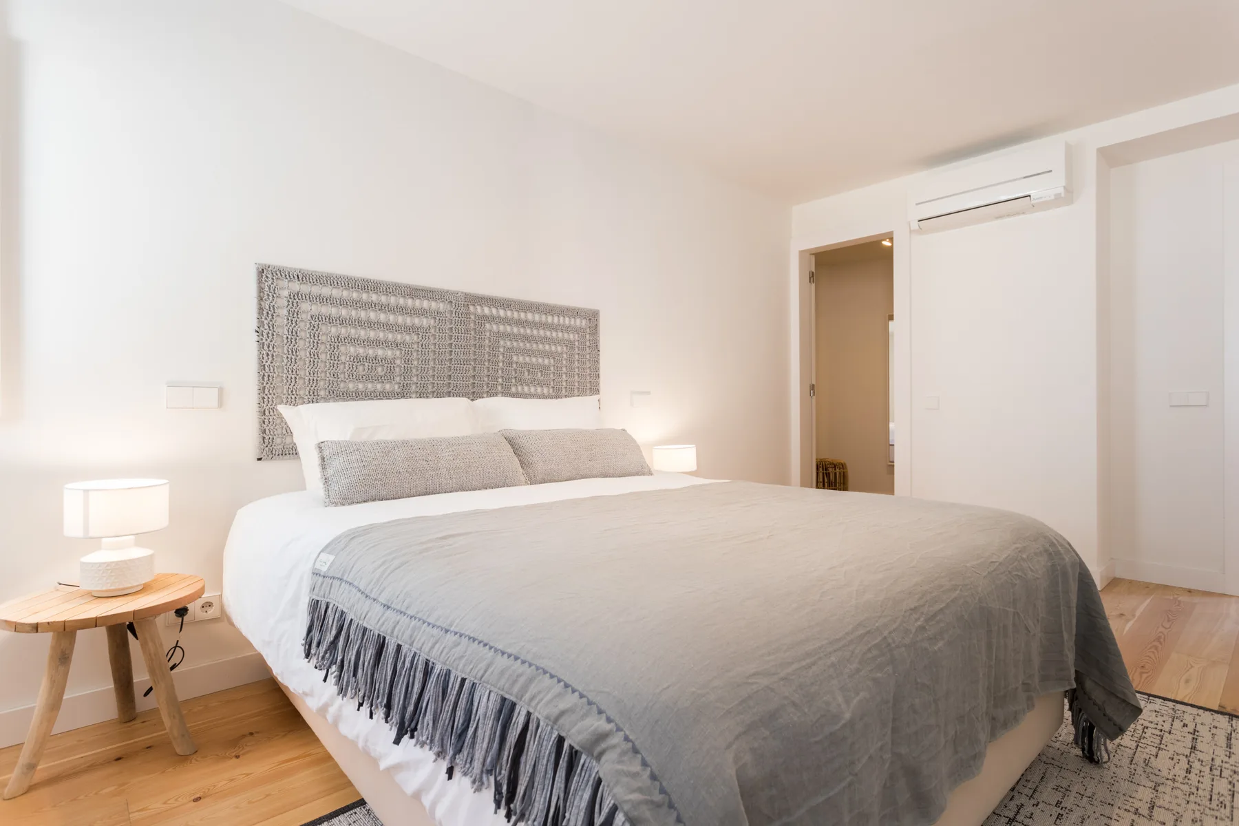 A bright bedroom with a bed and patterned headboard.