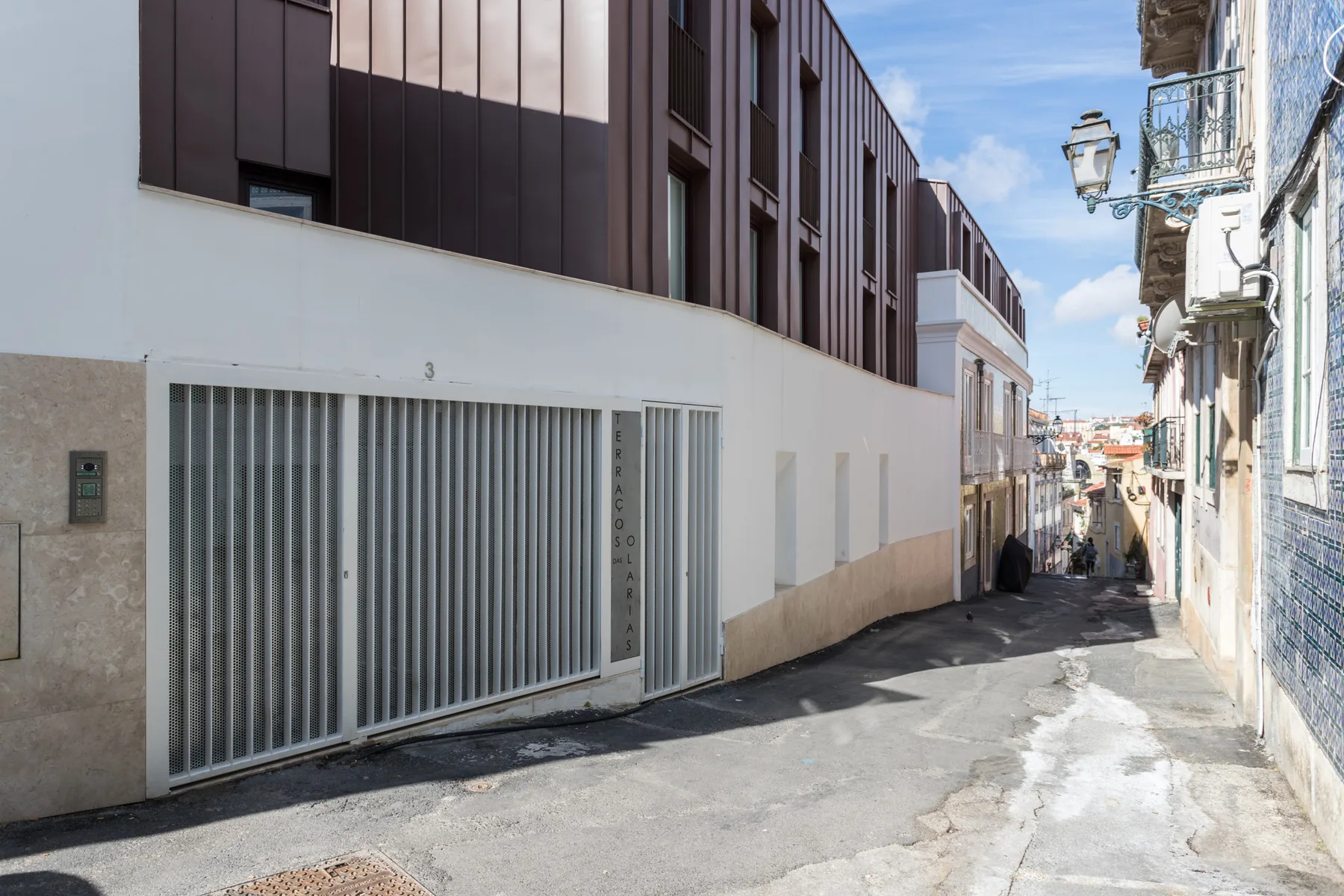 A narrow urban street runs between modern buildings and older façades.