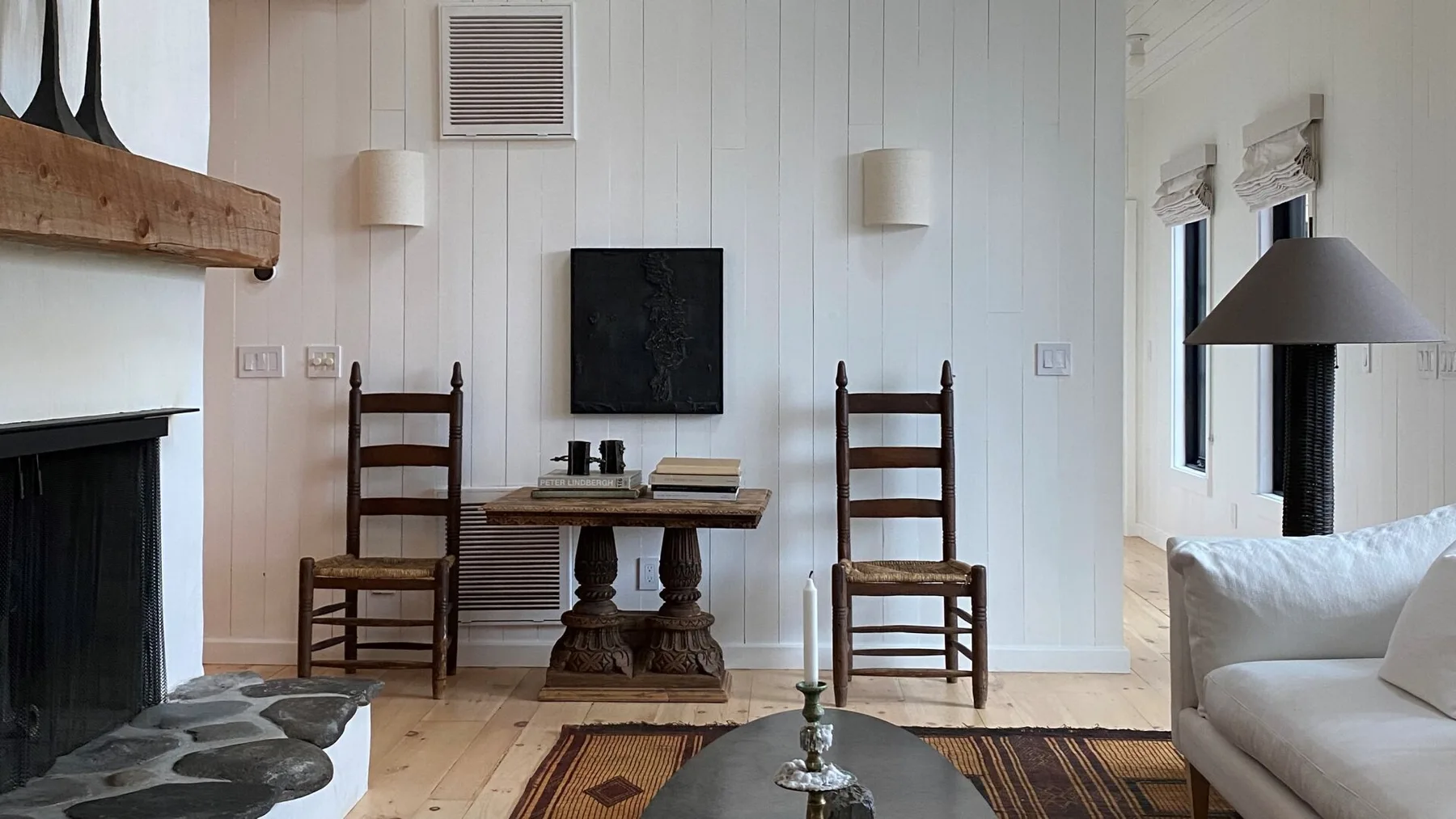 A bright sitting room with a fireplace, wall-mounted television, and wooden seating.