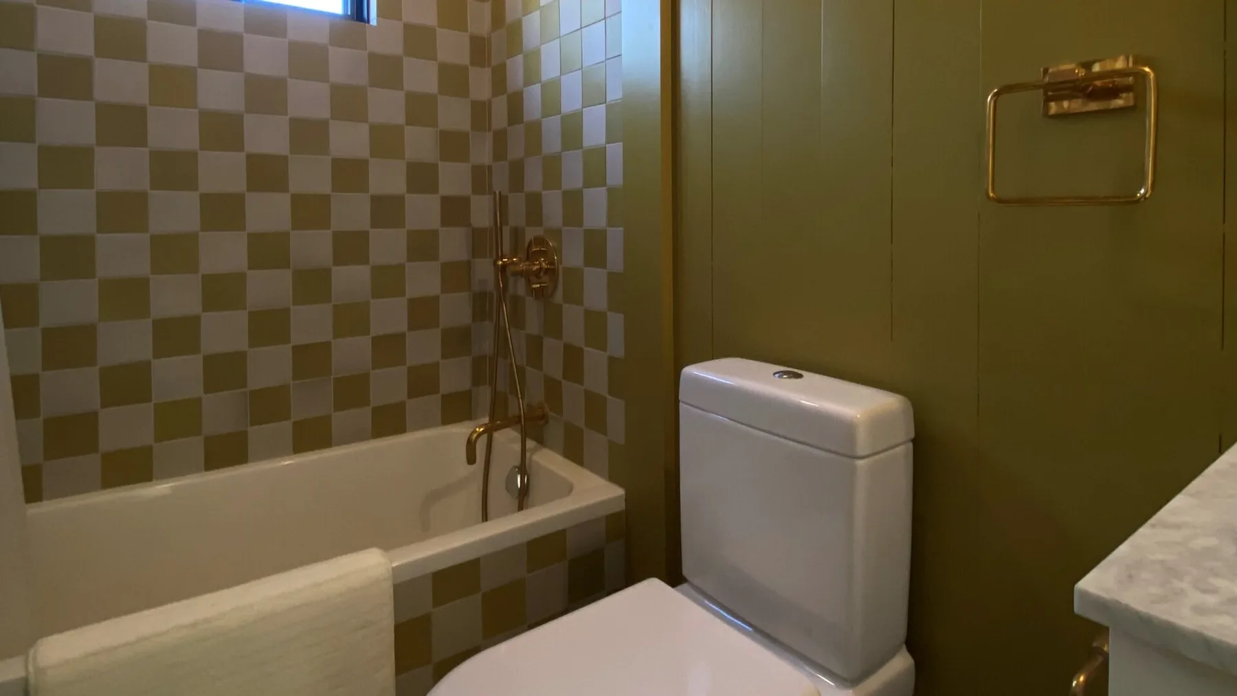 A bathroom with a bathtub, tiled wall, and toilet.
