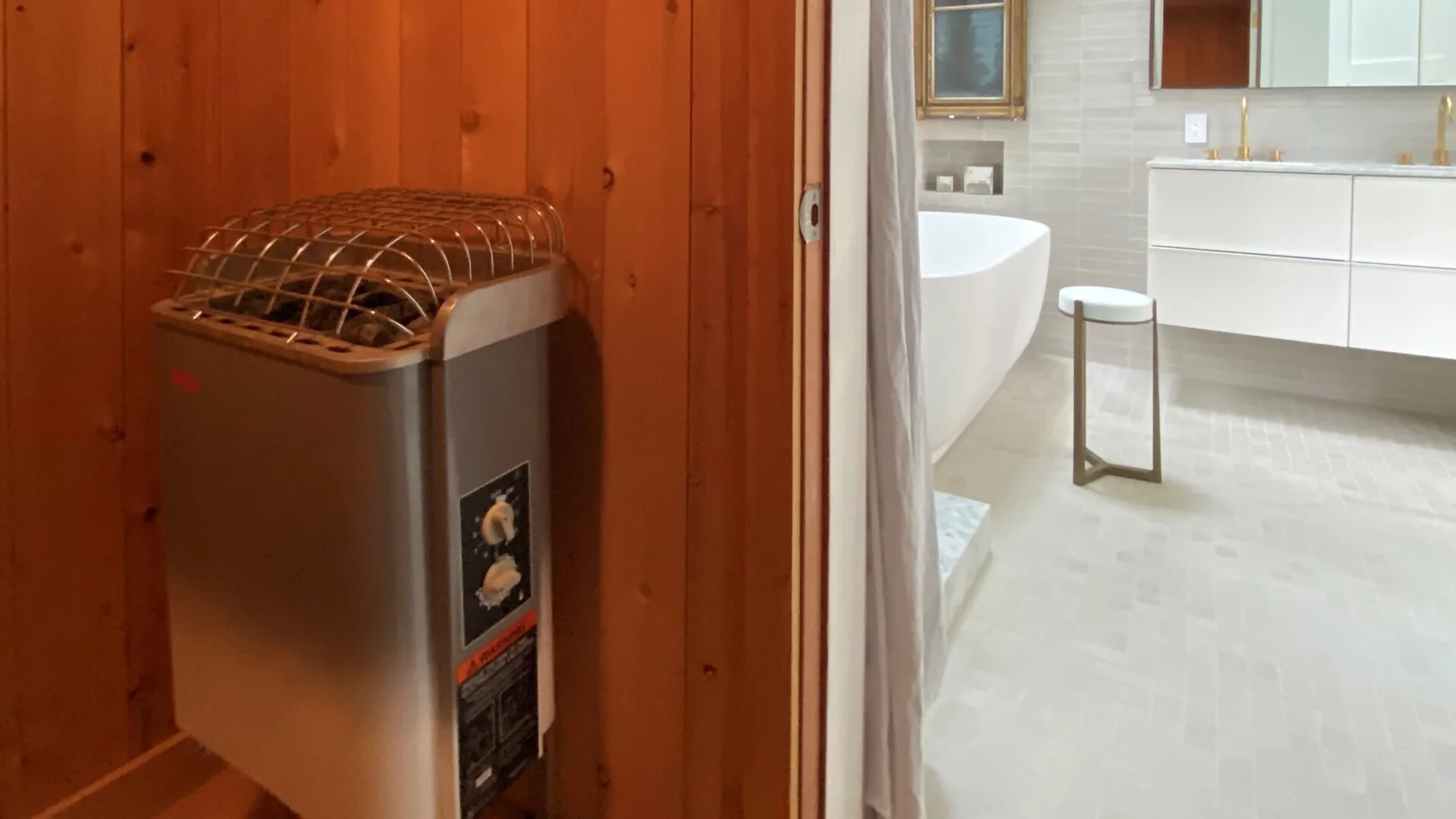 A sauna heater beside a bright bathroom with a bathtub and vanity.