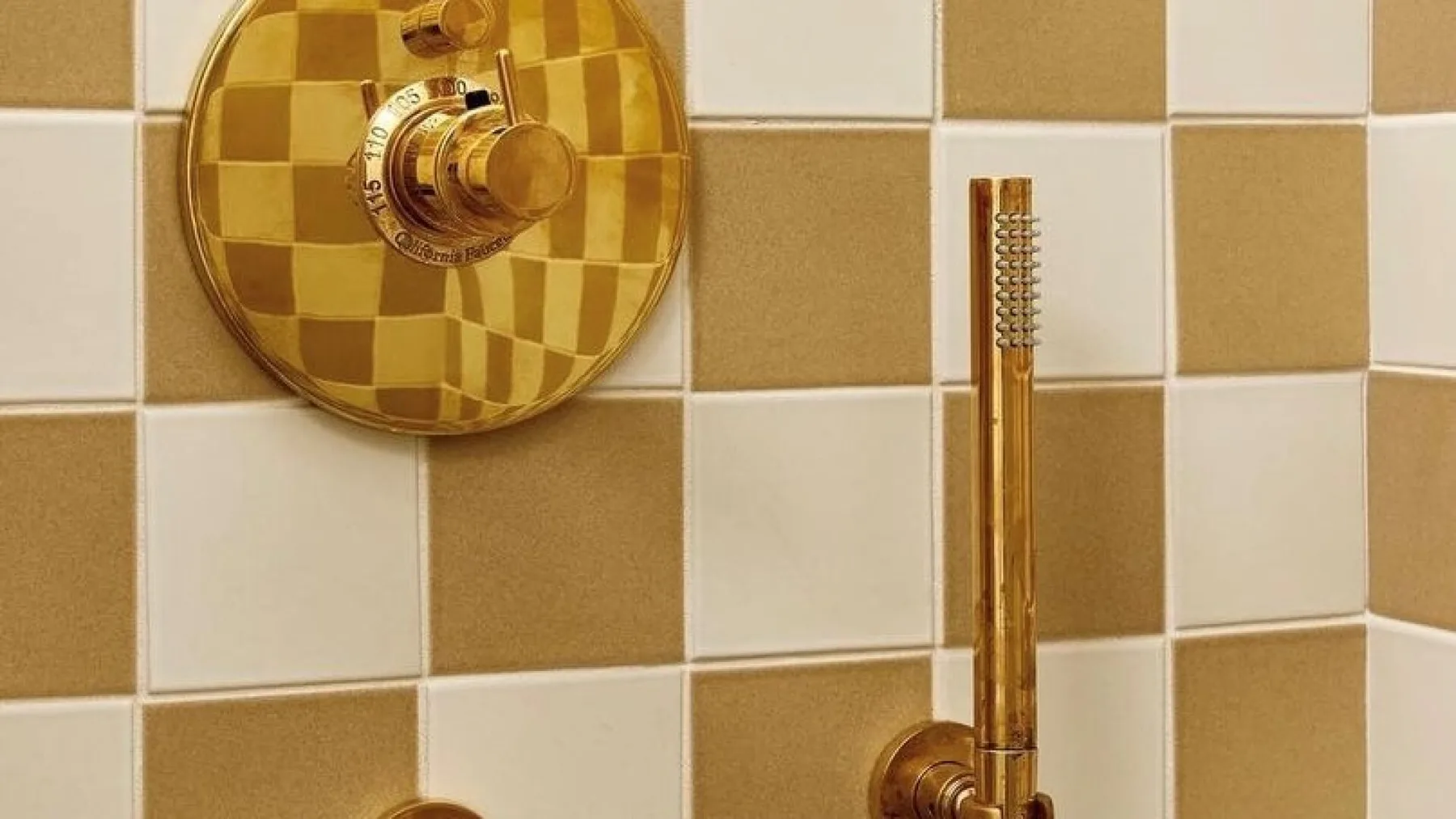 A bathroom shower with gold-colored fixtures against a checkerboard tile wall.