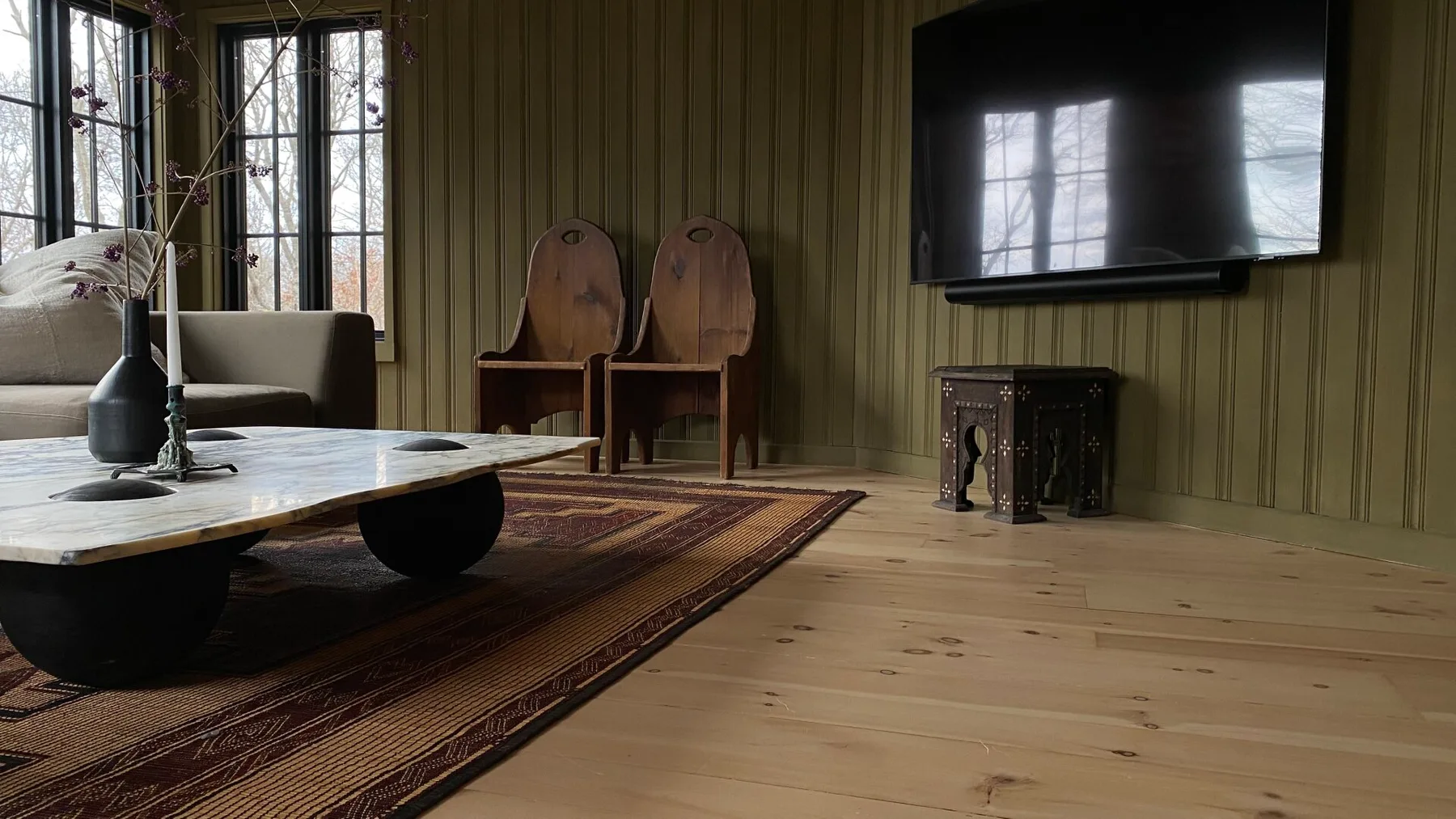 A living room with a low table, seating, and a wall-mounted television.