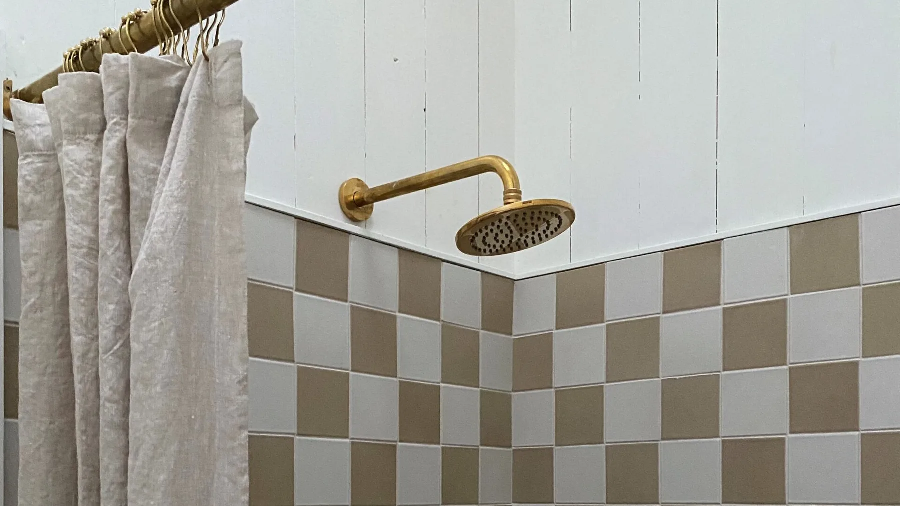 A shower area with a curtain, tiled walls, and a wall-mounted showerhead.