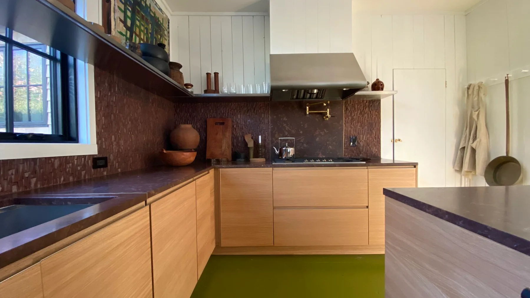 A modern kitchen with wooden cabinets, a dark countertop, and a window.