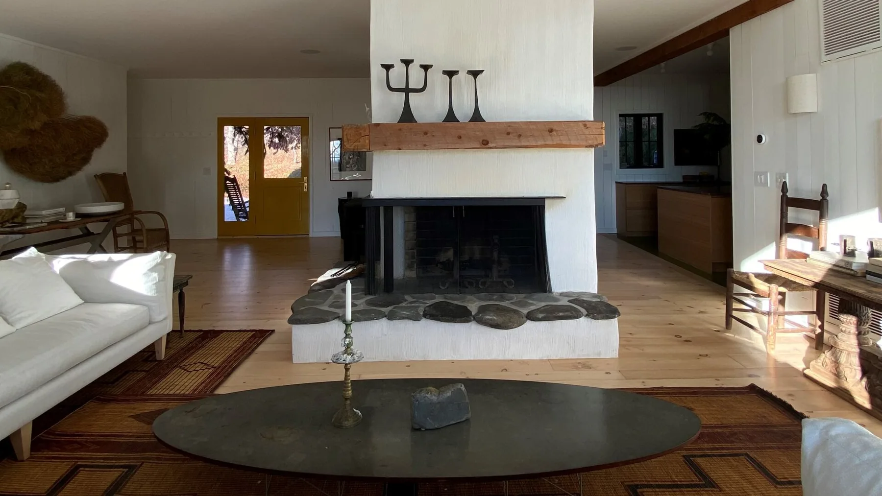 A bright open-plan living room centers on a white fireplace and a low coffee table.