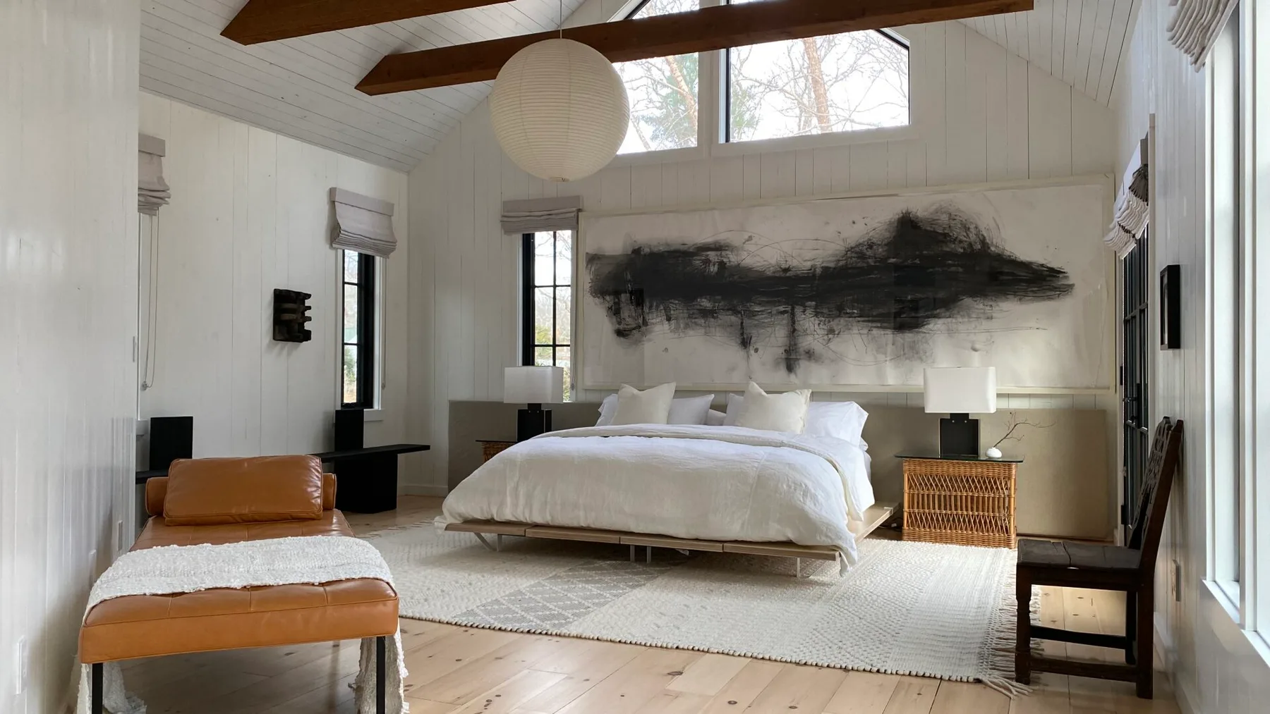 A bright bedroom with a white bed and large abstract artwork on the wall.