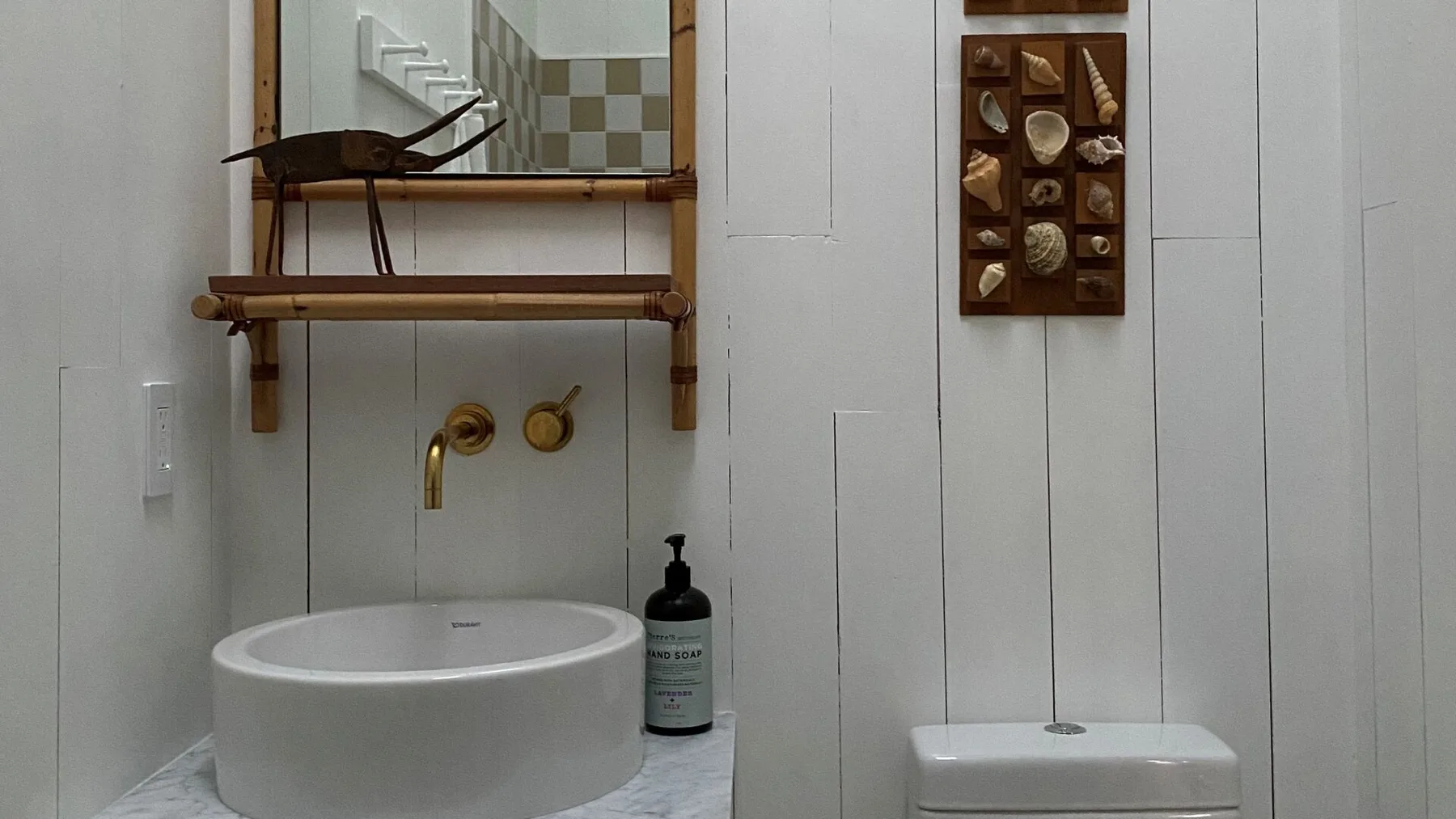 A bathroom vanity with a round vessel sink, wall-mounted faucet, and framed wall decor.