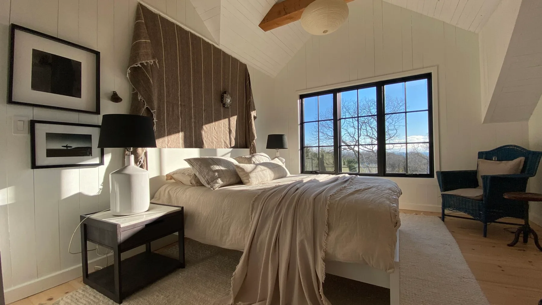 A bright bedroom with a bed beneath a large window.