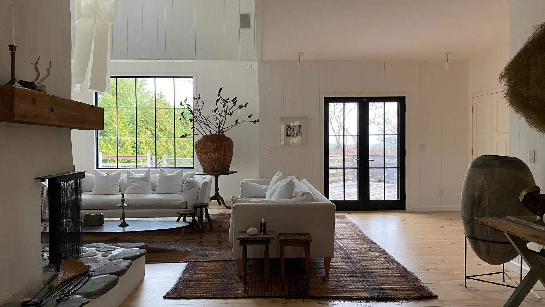 A bright living room with seating arranged around a low table and large windows.