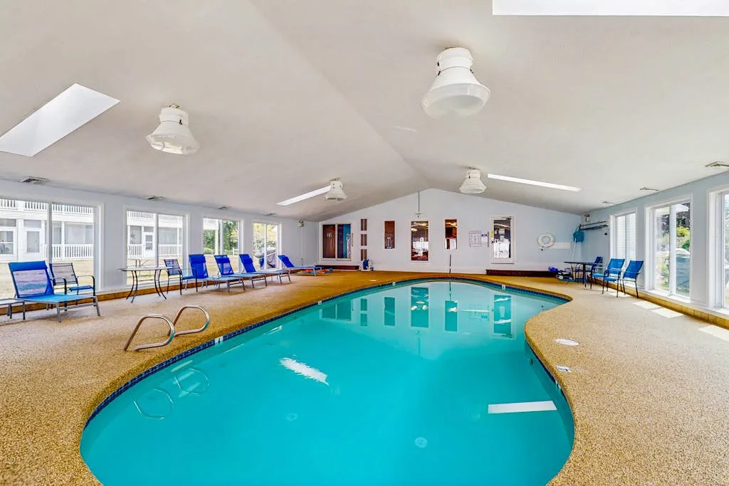 An indoor swimming pool with blue seating arranged along the windows.