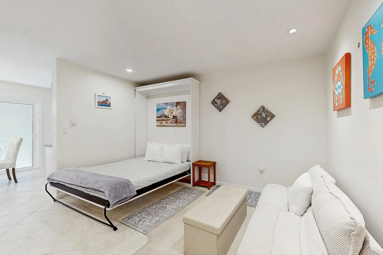 Un dormitorio luminoso con una cama y un sofá blanco.