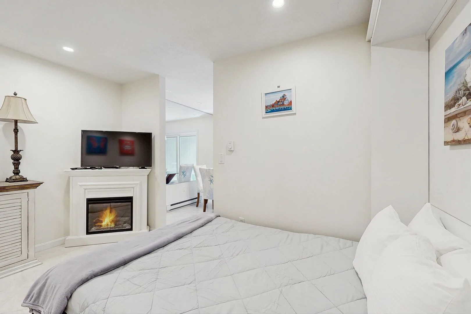 A bedroom with a neatly made bed, a television, and a fireplace.