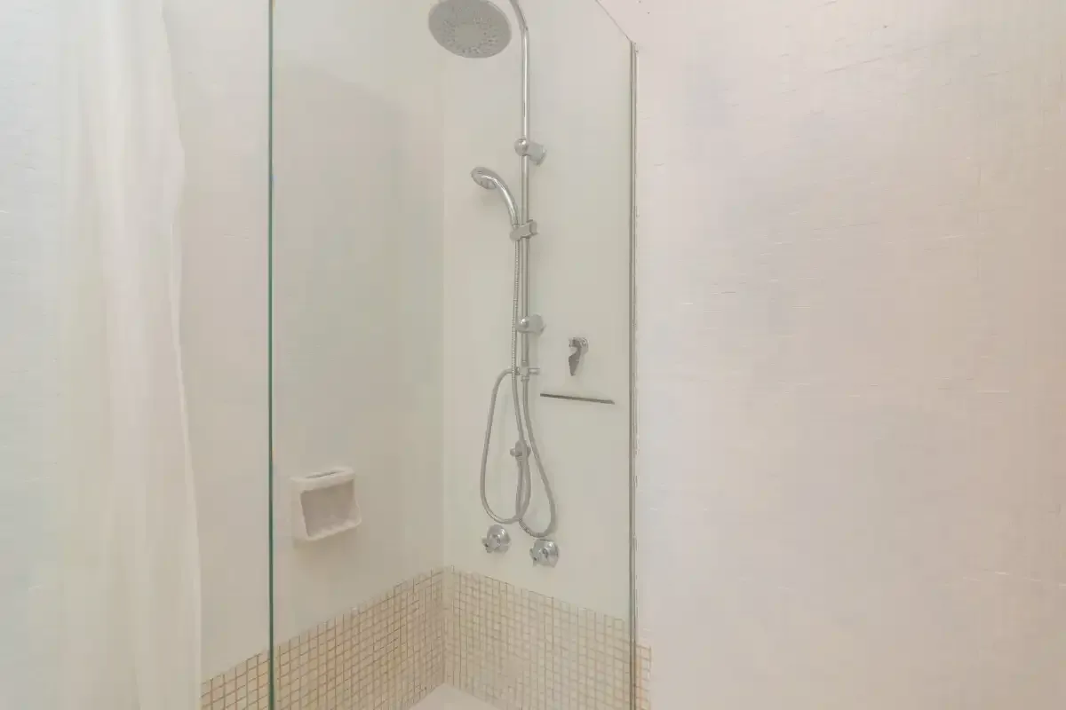 A bathroom shower with a handheld showerhead and tiled lower walls.