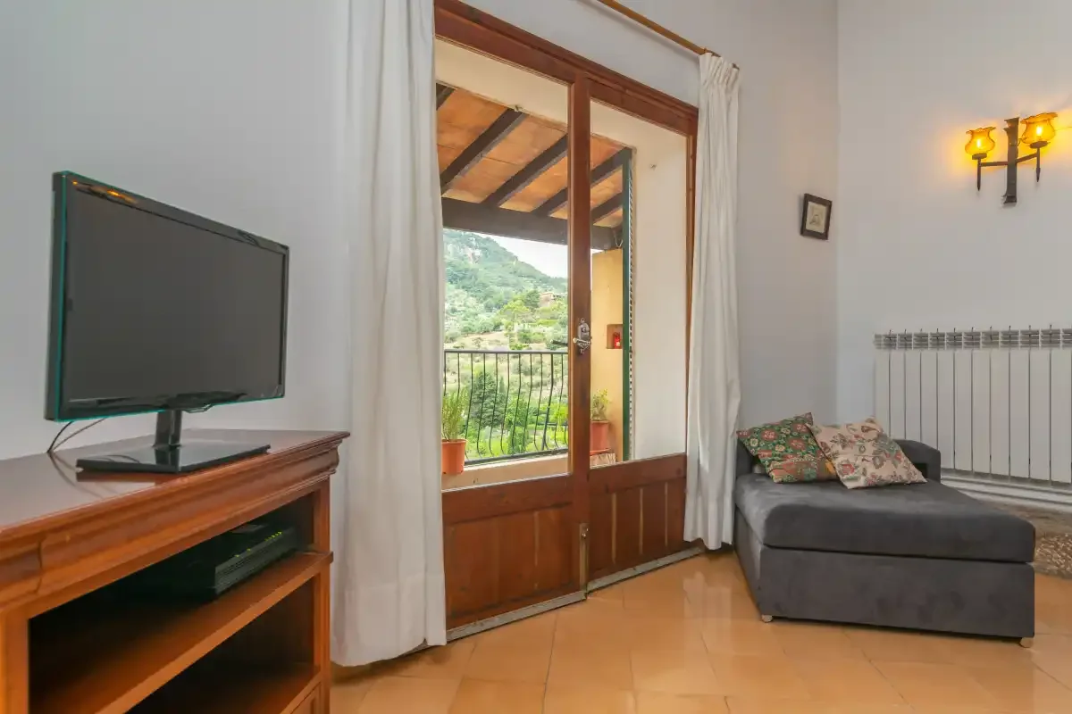 A living room with a television, seating, and glass doors opening onto a balcony.