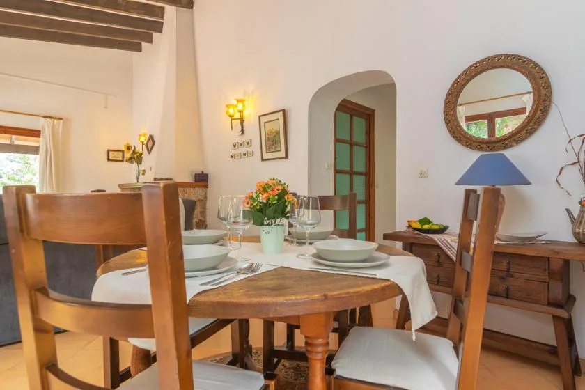 A dining room with a wooden table set with plates and flowers.
