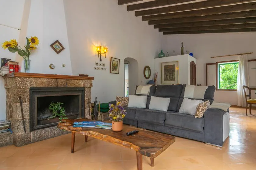A living room with gray seating, a stone fireplace, and a wooden coffee table.