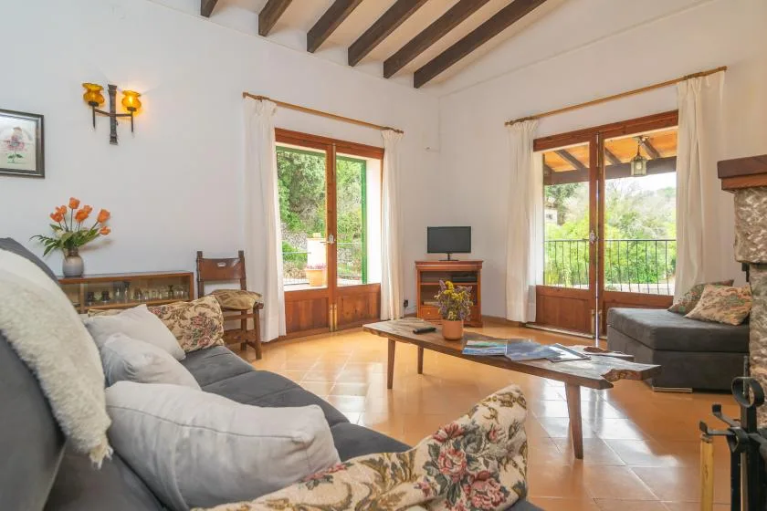 A bright living room with seating, a coffee table, and tall glass doors opening onto a balcony.