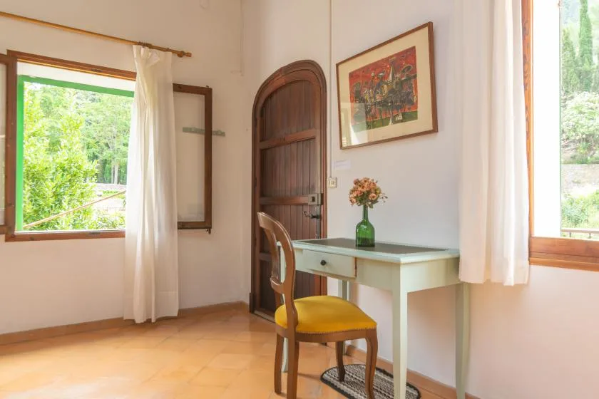 A bright room with a desk, chair, and windows overlooking greenery.
