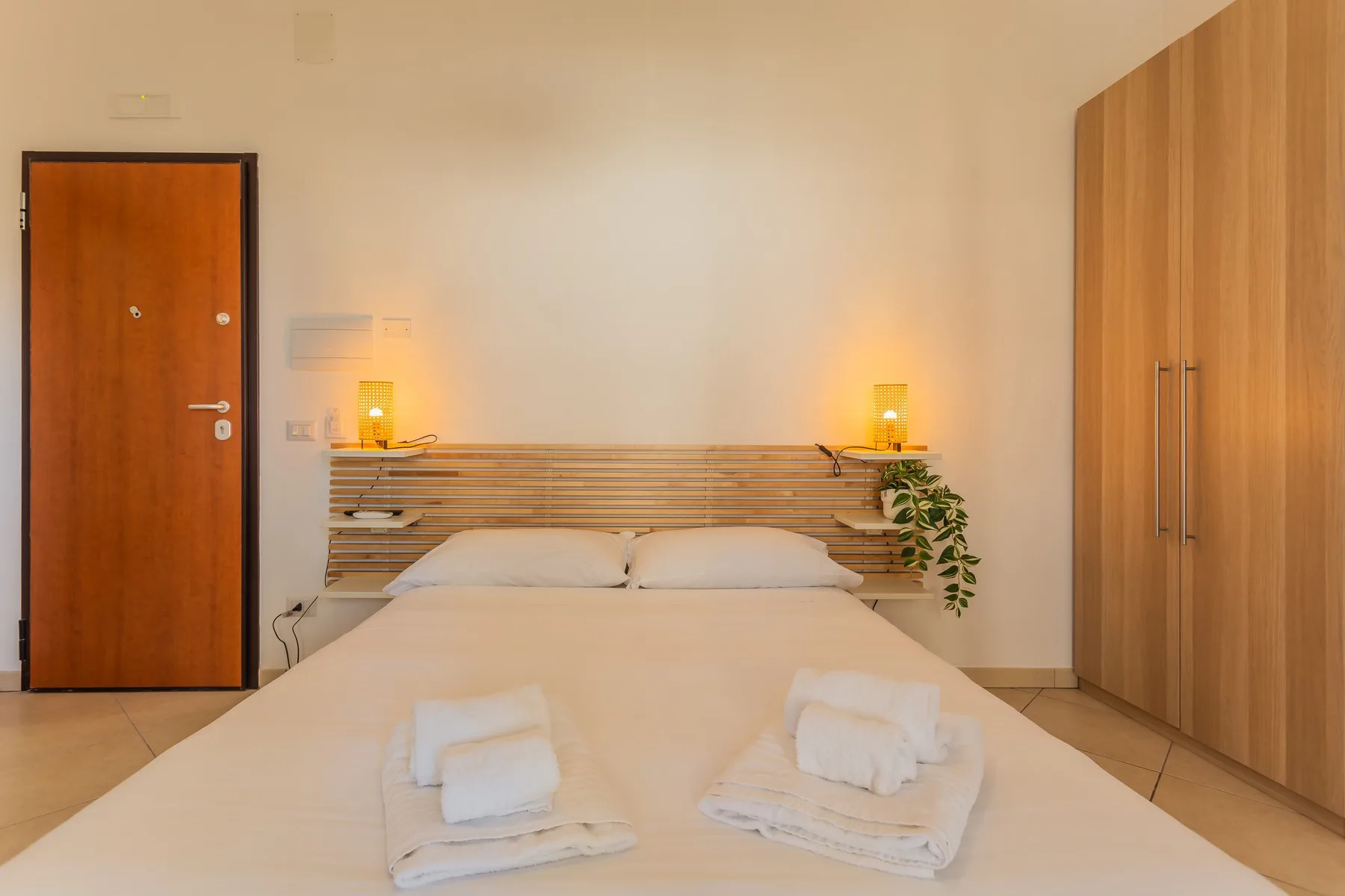 A bedroom with a neatly made bed and a wooden wardrobe.