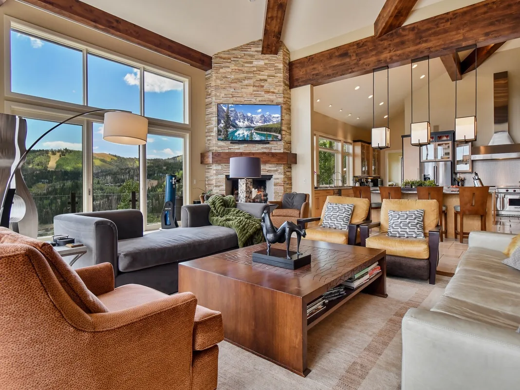 A spacious living room with seating around a coffee table and a stone fireplace.