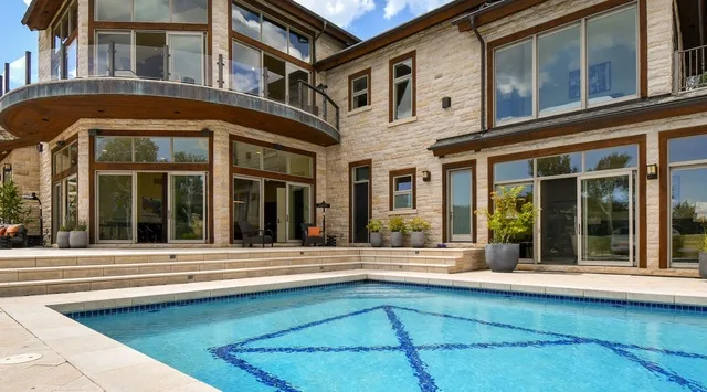 A swimming pool sits beside a modern house with large windows.