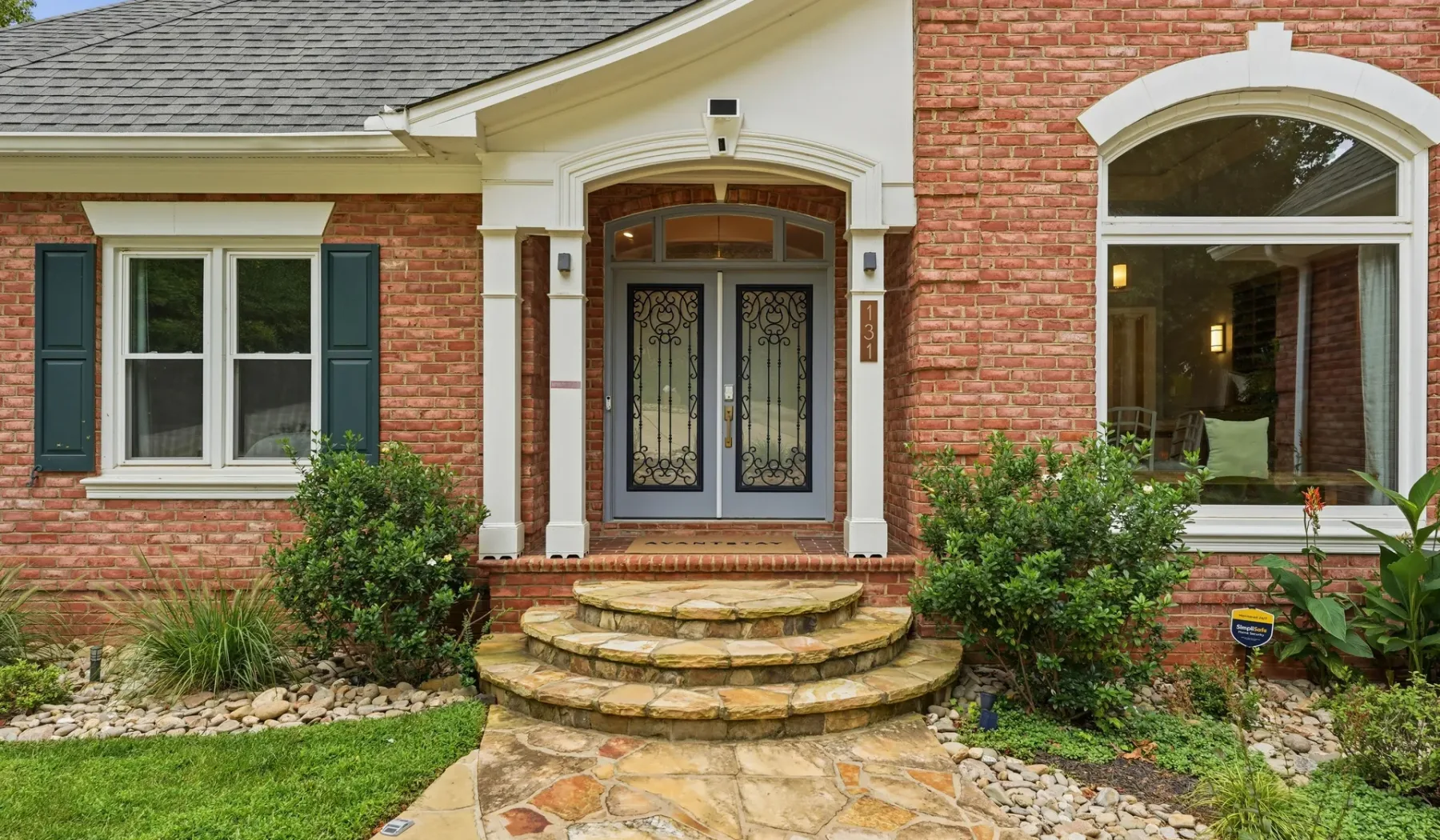 A brick house entrance with an arched doorway and curved stone steps.