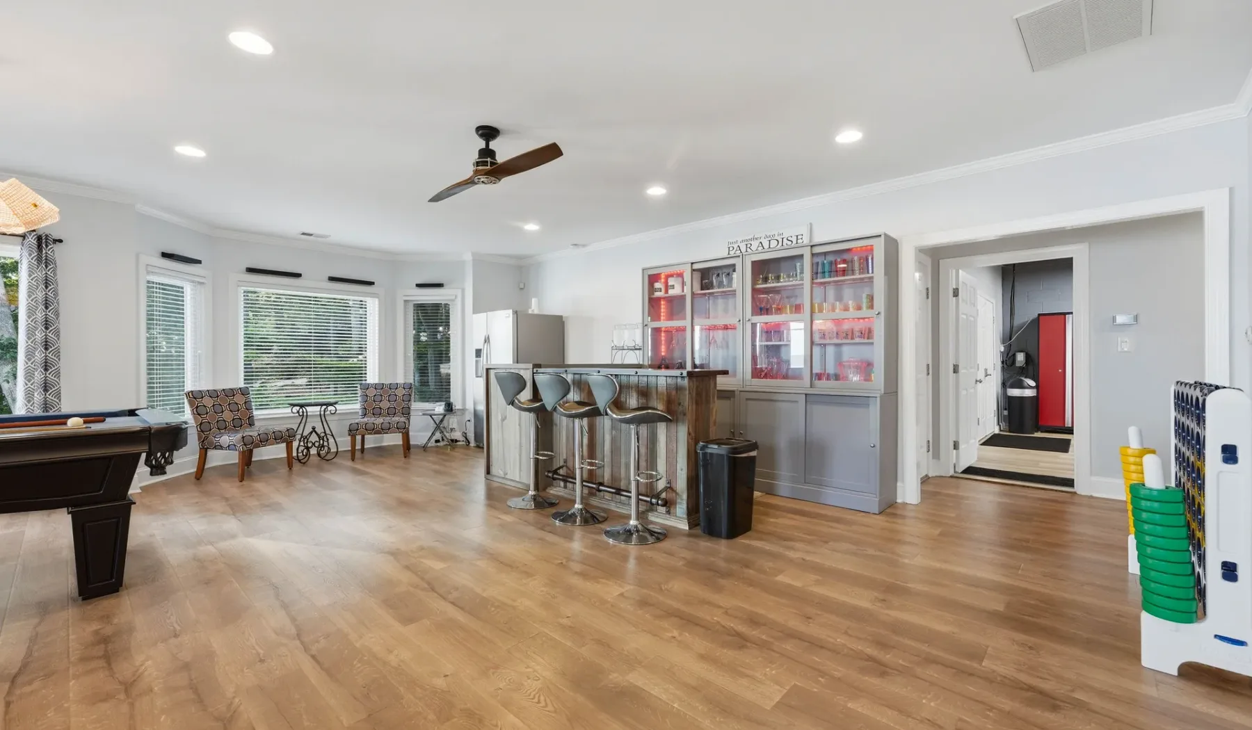 A bright game room with a pool table, counter seating, and wall displays.
