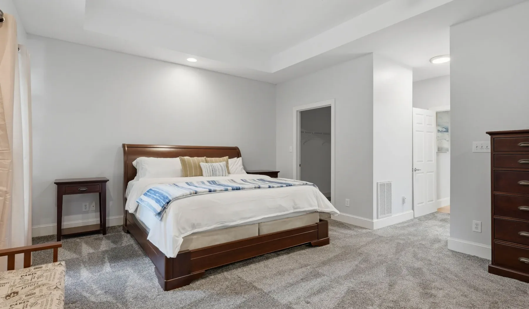 A bedroom with a wooden bed, bedside tables, and carpeted flooring.