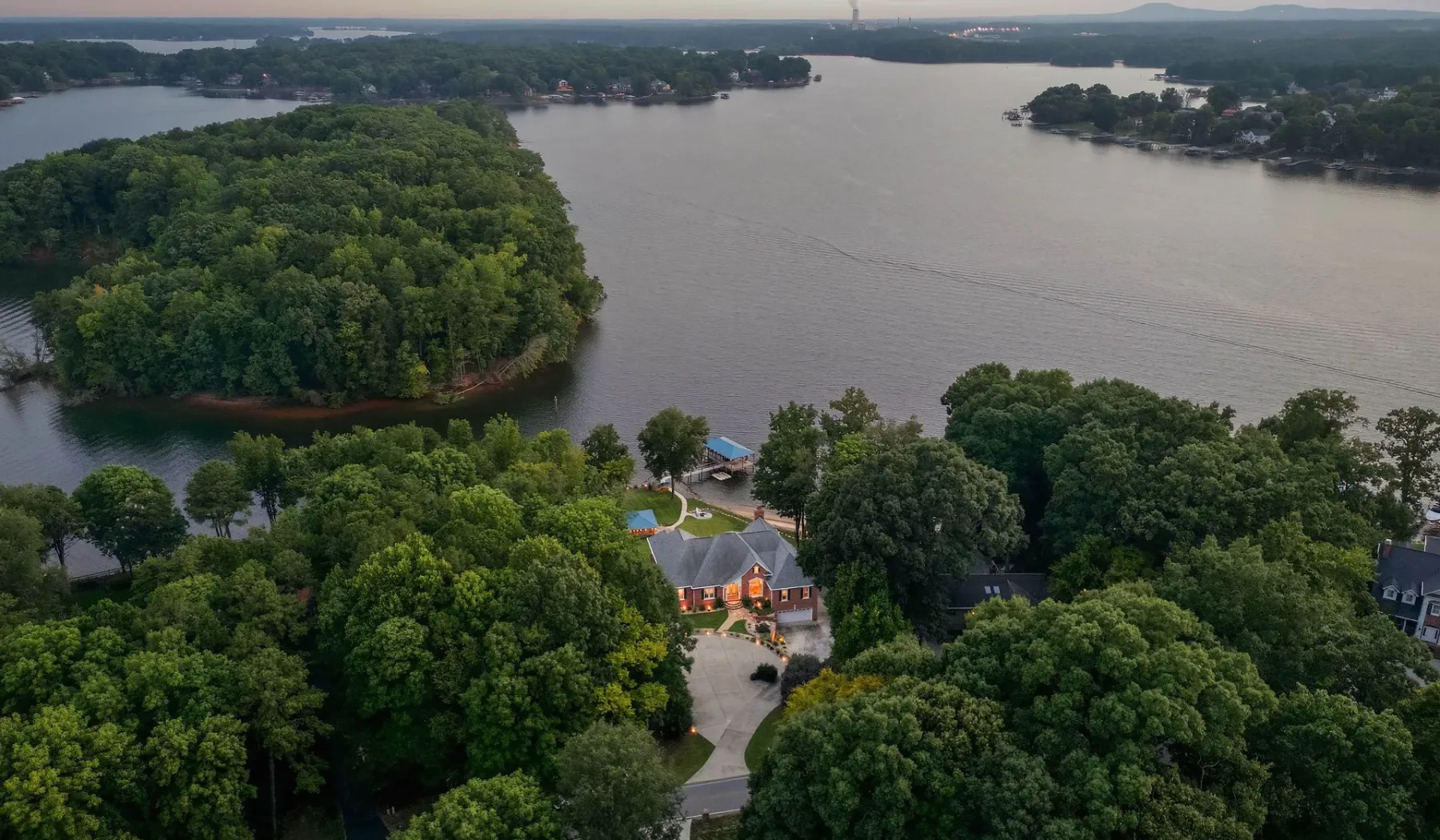 An aerial view of a lakeside house surrounded by trees.