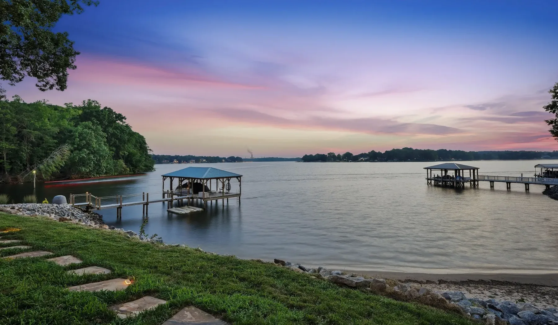 A calm waterfront scene at sunset, with small piers extending over the water.