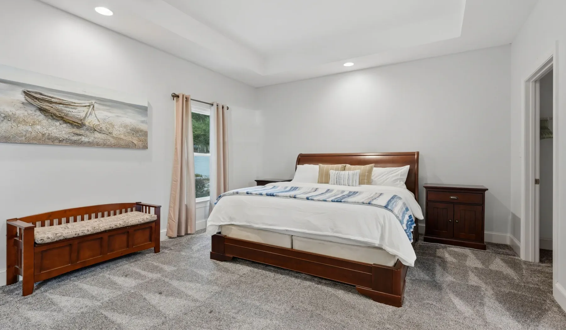 A bedroom with a wooden bed, light bedding, and a low storage bench.