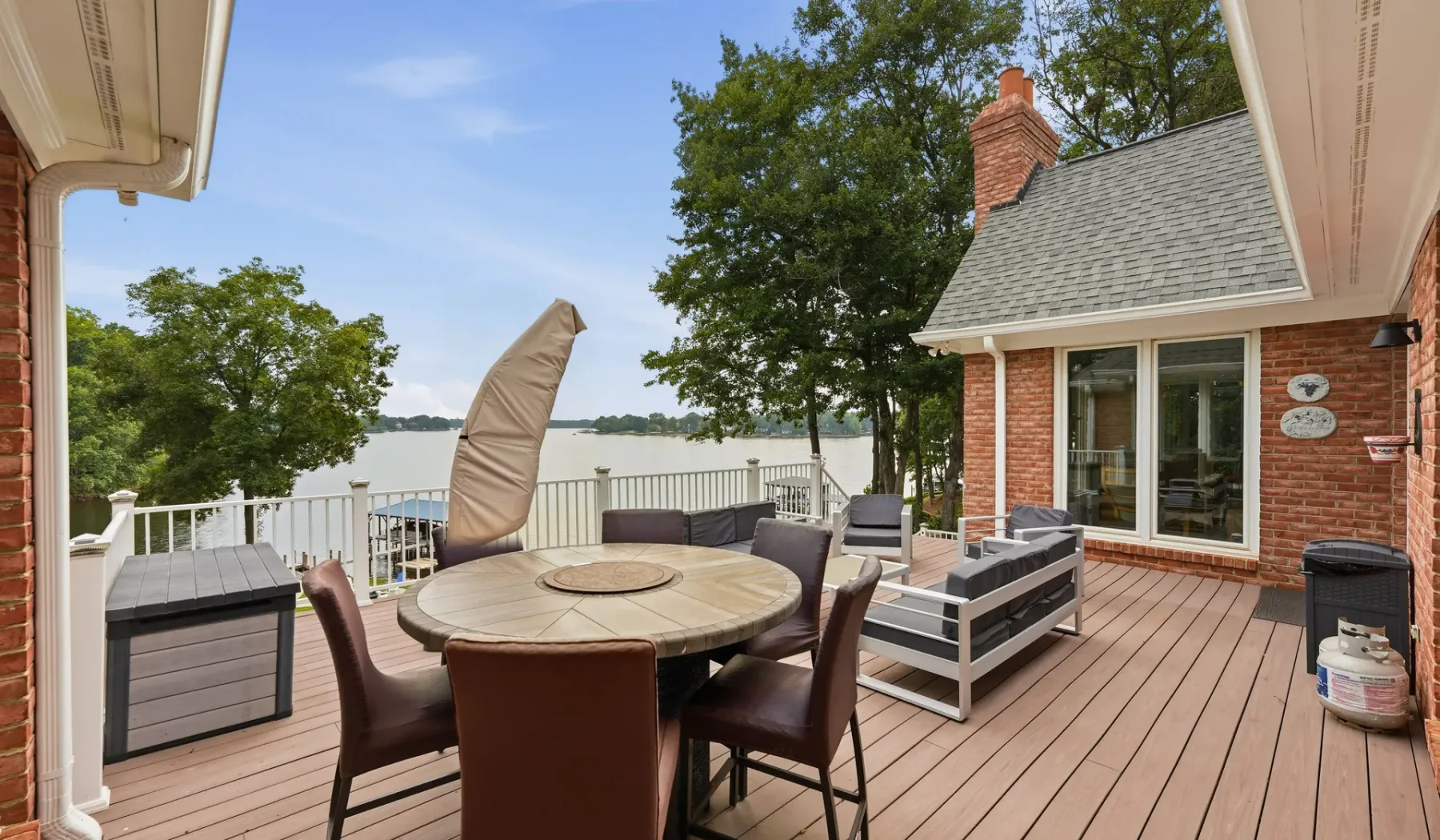 A lakeside deck with a dining table and outdoor seating overlooks the water.