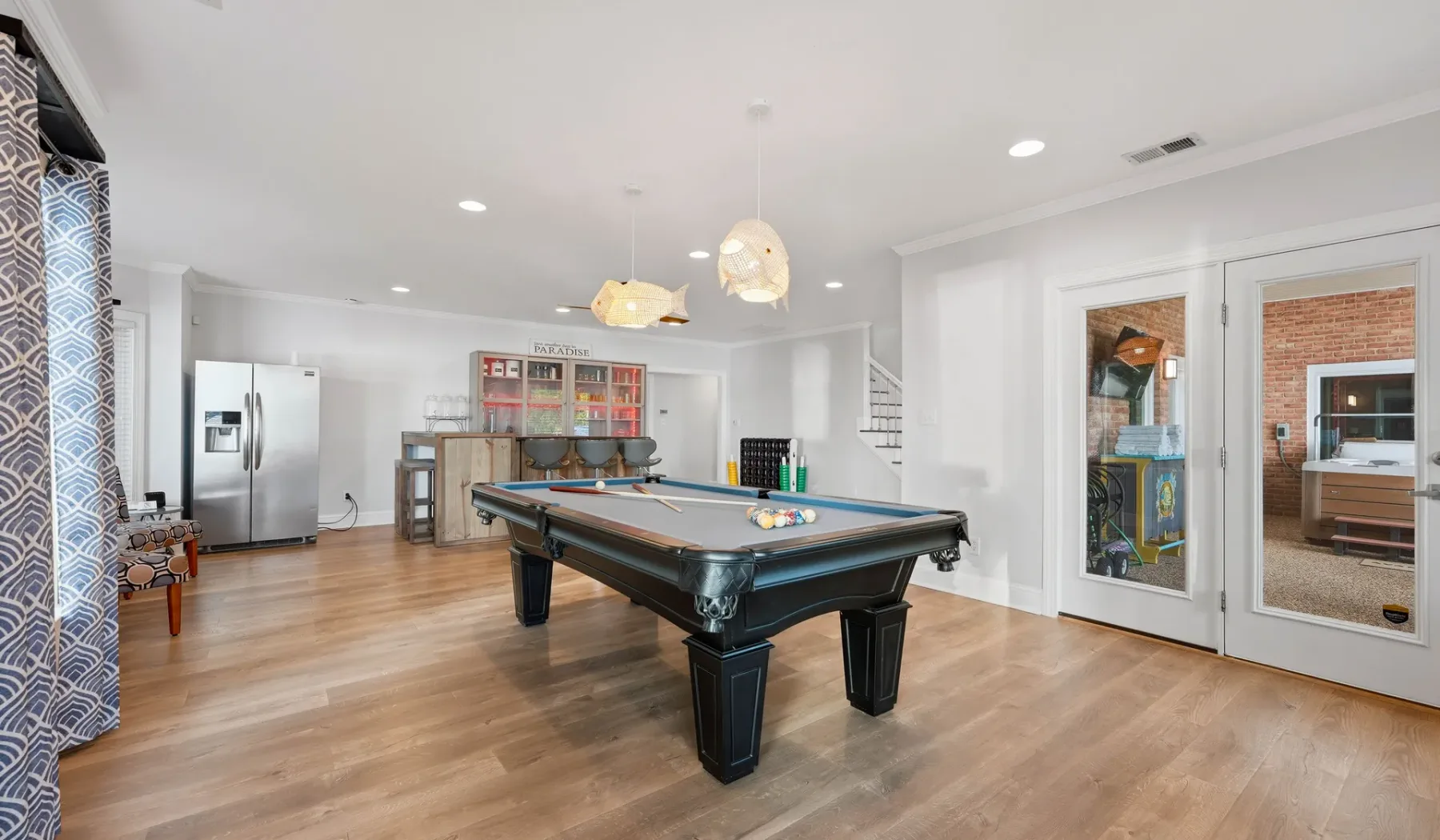 A bright game room features a pool table and light wood flooring.