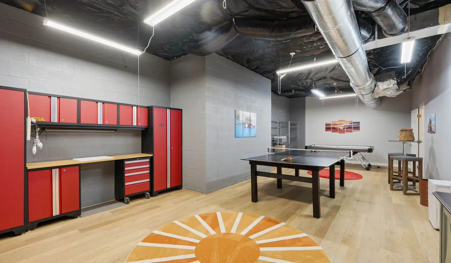 A recreation room with a pool table and red tool cabinets.