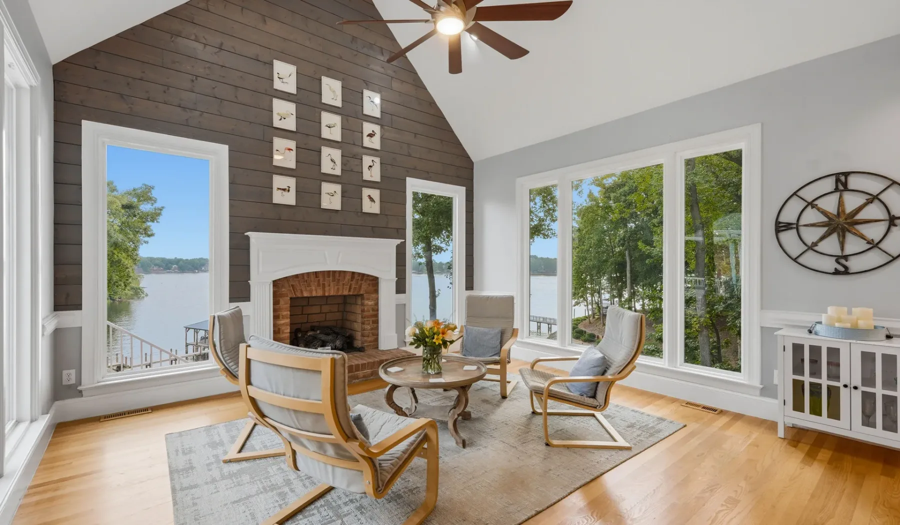A bright living room with seating arranged around a fireplace and large windows.
