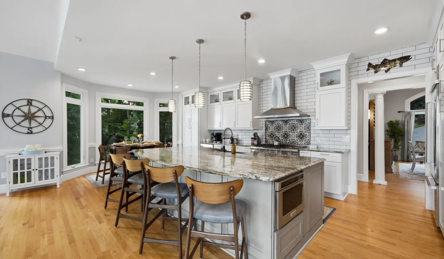 A bright kitchen with a large island and seating beside a dining area.