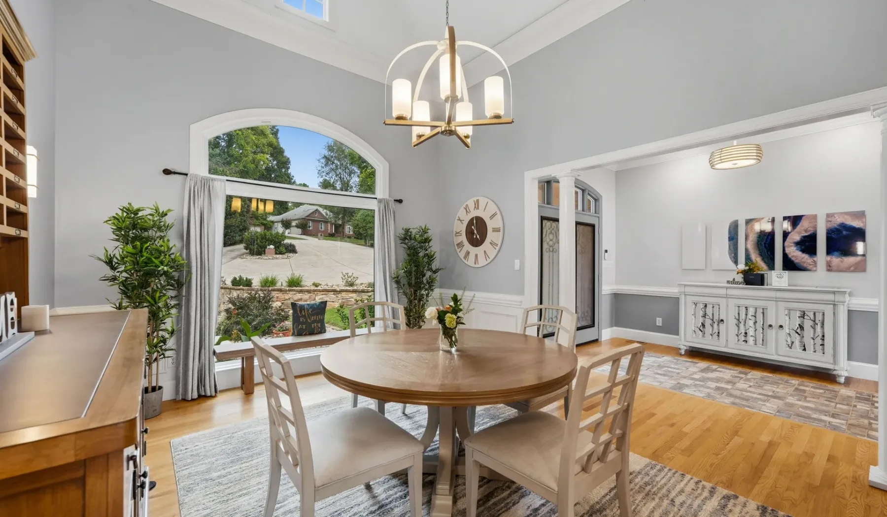 A dining room with a round wooden table beneath a chandelier.