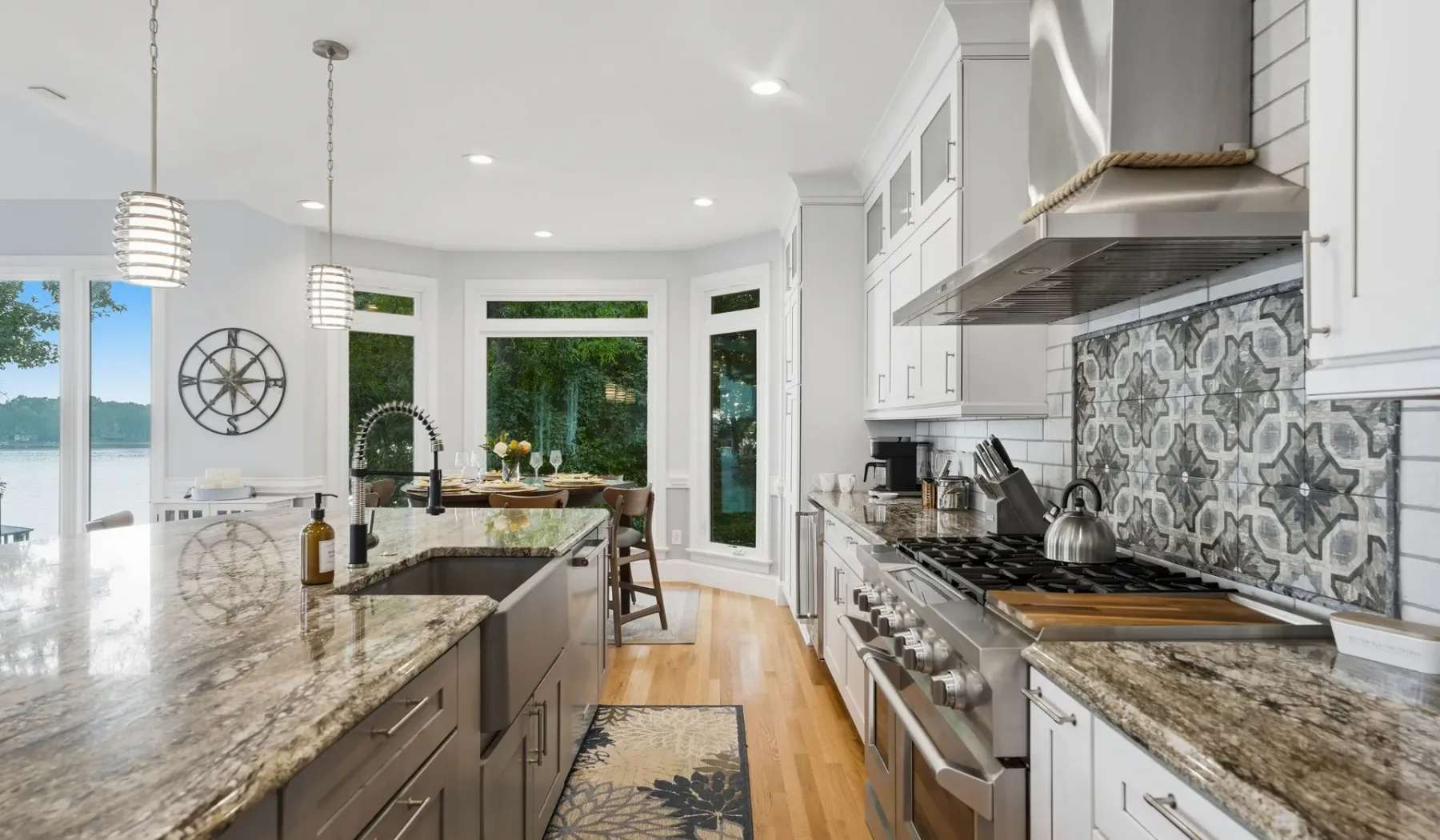 A bright kitchen with a central island, large windows, and patterned backsplash.