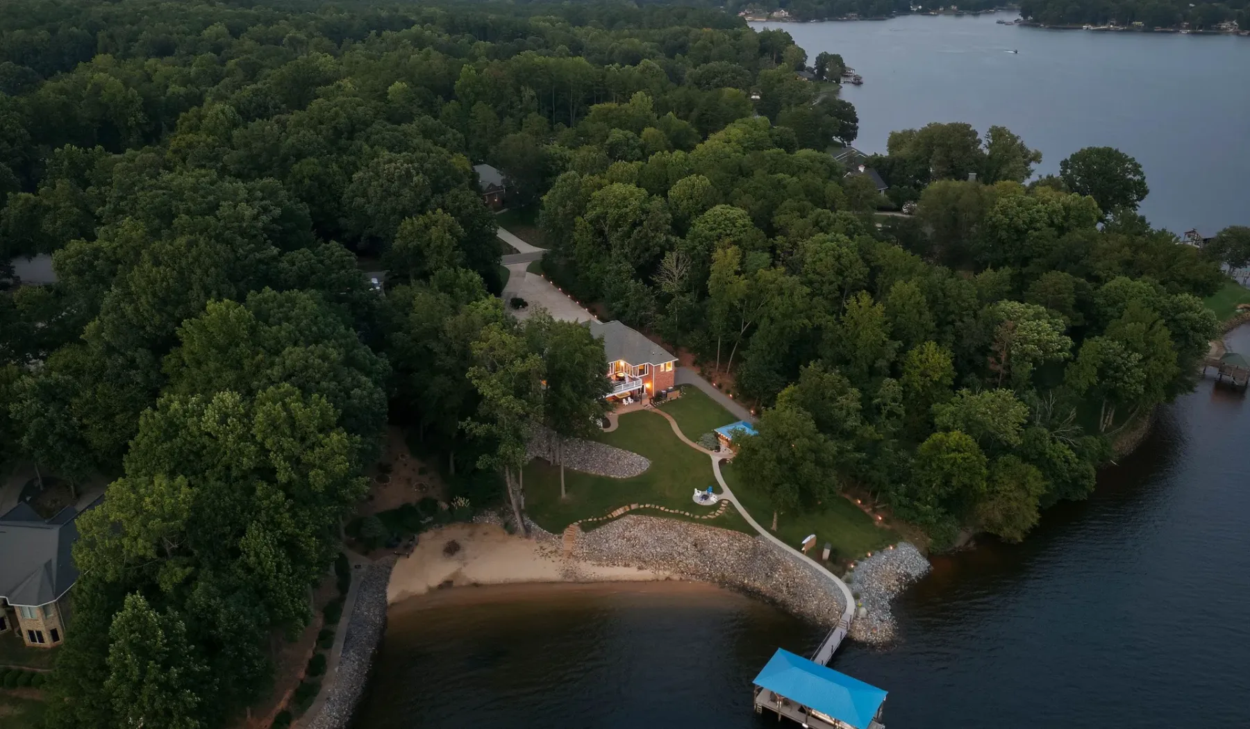 Aerial view of a wooded lakeside property with a shoreline and small dock.