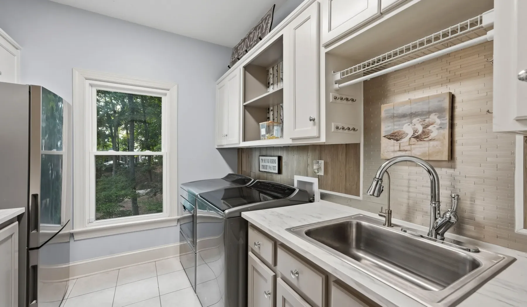 A bright laundry room with a washer, dryer, and deep utility sink.